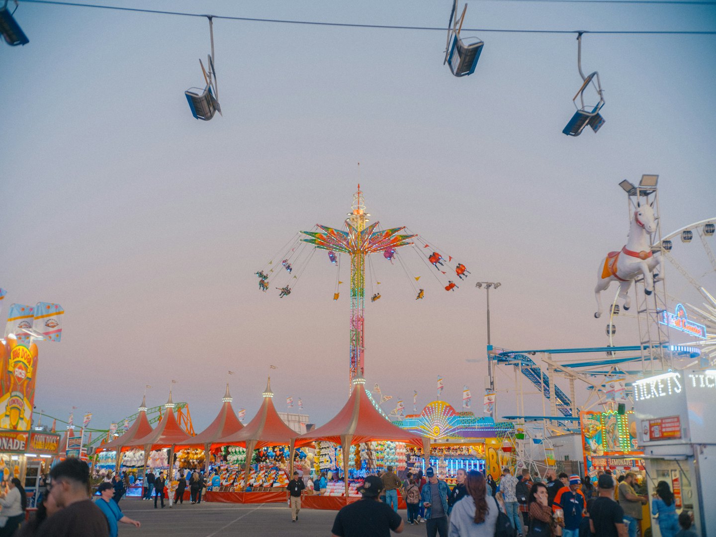 Karneval in der Dämmerung mit beleuchteten Fahrgeschäften und Spielbuden.