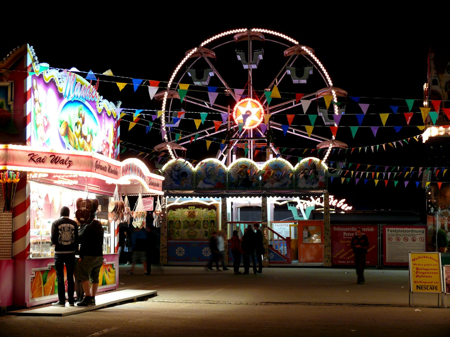 Menschen genießen Essensstände auf einem hell erleuchteten Nachtmarkt.